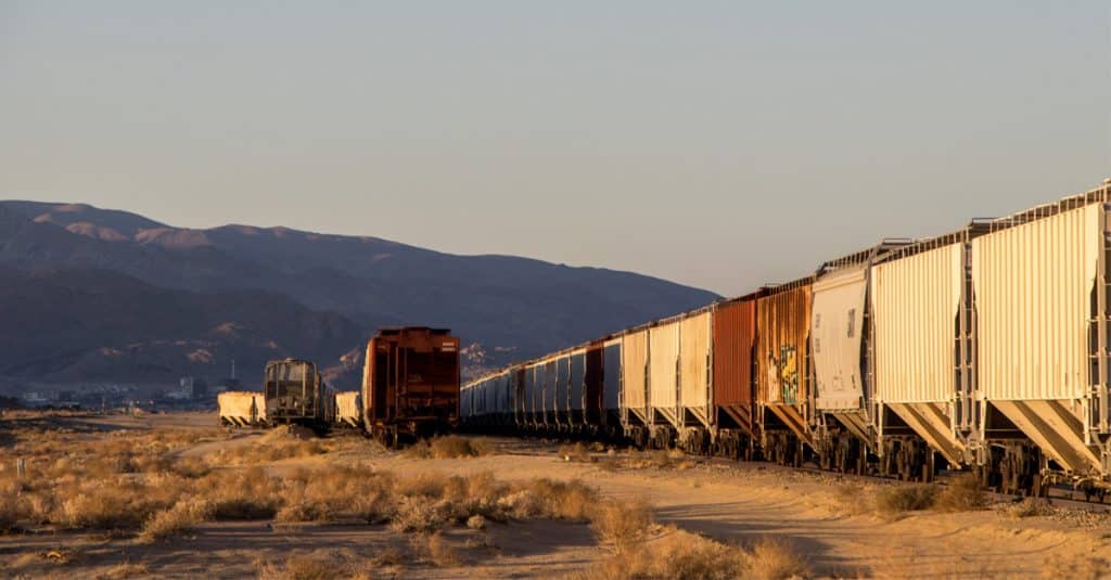 Sunset behind hills with rail cargo hoppers on the horizon.