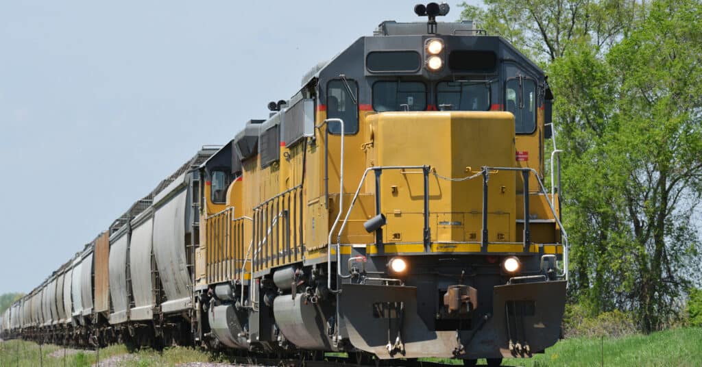 A rail freight locomotive with a line of rail shipping freight behind it.
