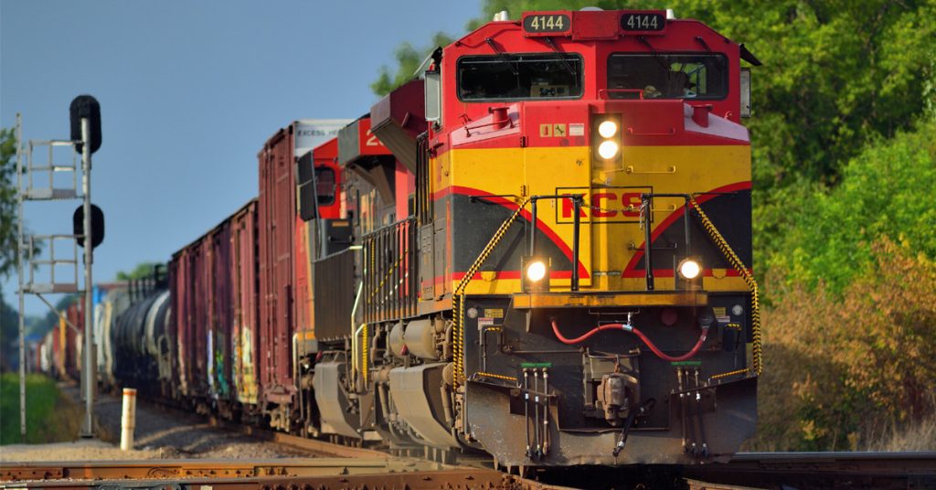 A Kansas City Southern train hauling rail freight along a railroad.