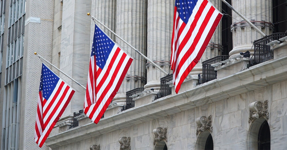 A columned federal building with three American flags flying. 