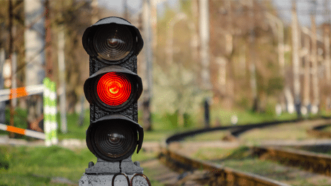 Rail semaphore stoplight with a red signal near a railway.